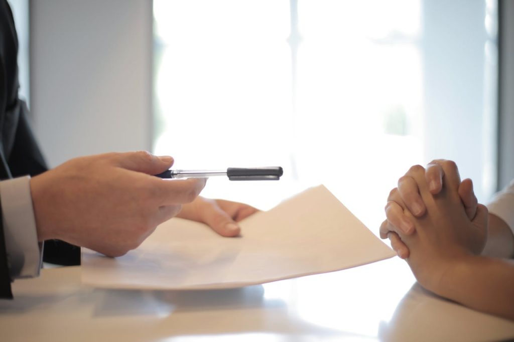A person holding a contract and a pen.